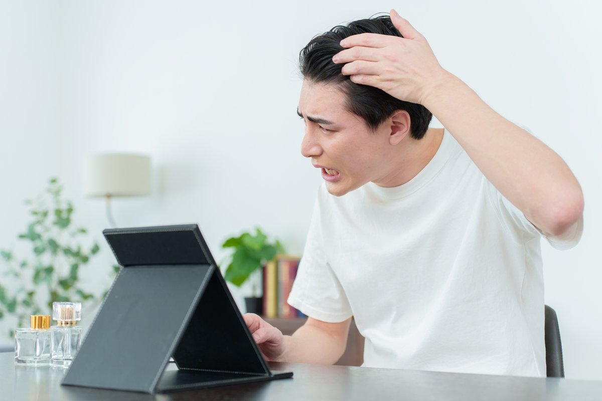 鏡を見て薄毛に悩む男性